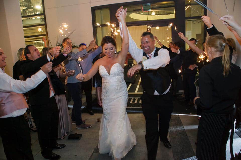 bride and groom holding hands while exiting wedding with guests holding sparklers on both sides of them